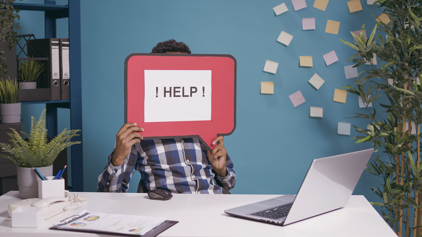 male-employee-holding-speech-bubble-with-text-message-ask-help-while-he-works-laptop-plan-business-strategy-project-manager-showing-card-board-with-writing-cartoon-mockup.jpg